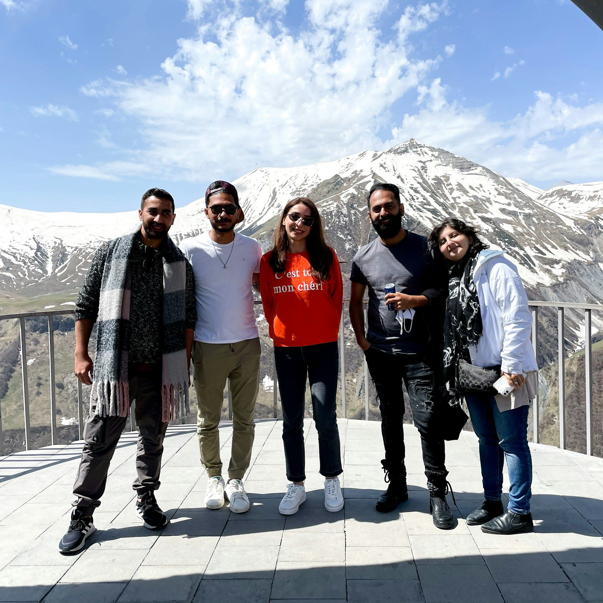 Nia with guests on a snowy viewpoint terrace above Gudauri, the Caucasus behind them